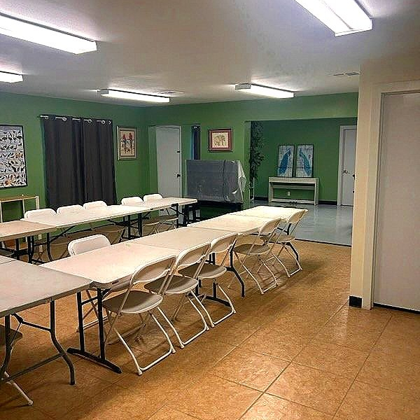 Interior view of a room featuring multiple folding tables and chairs arranged in a row.